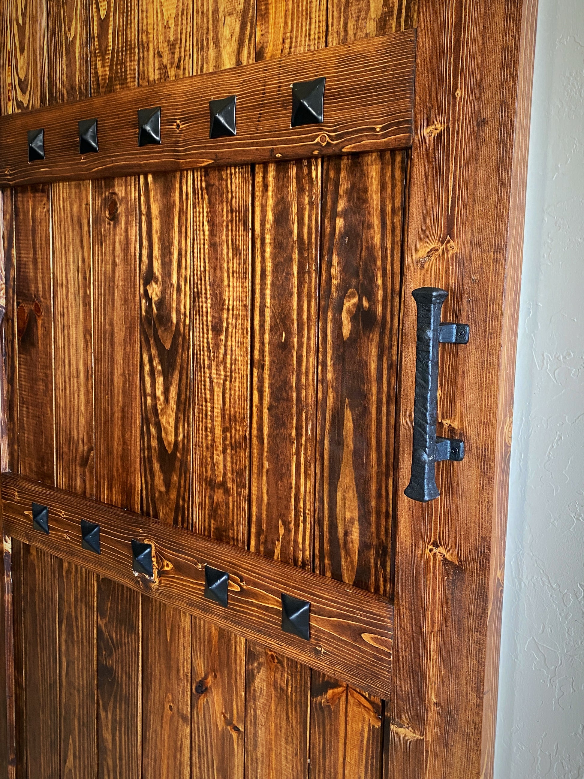 custom barn door hardware detail black pyramid studs and hammered iron handle dark wood handcrafted