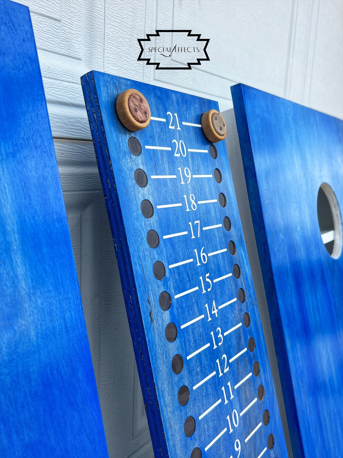 close up handcrafted cornhole scoreboard with engraved Western knob pegs natural wood