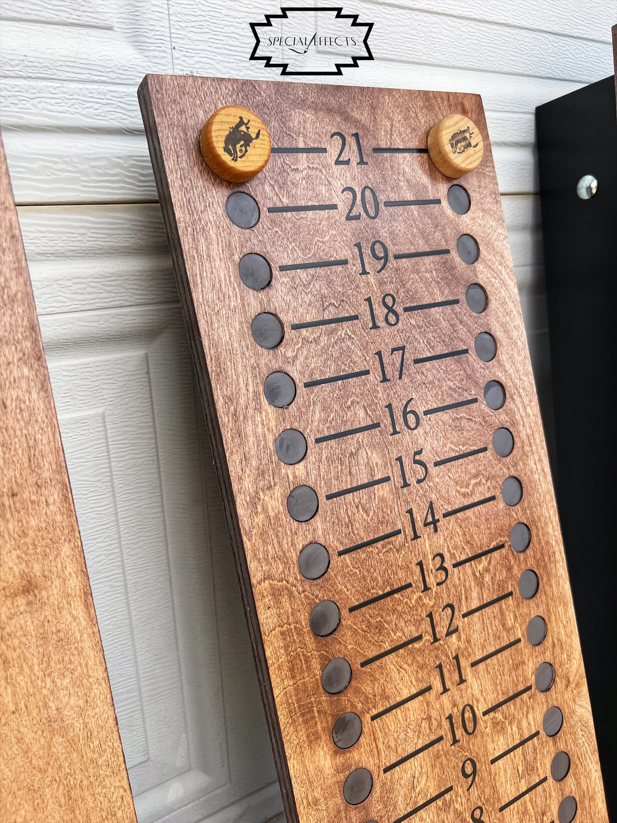 close up handcrafted cornhole scoreboard with engraved Western knob pegs natural wood