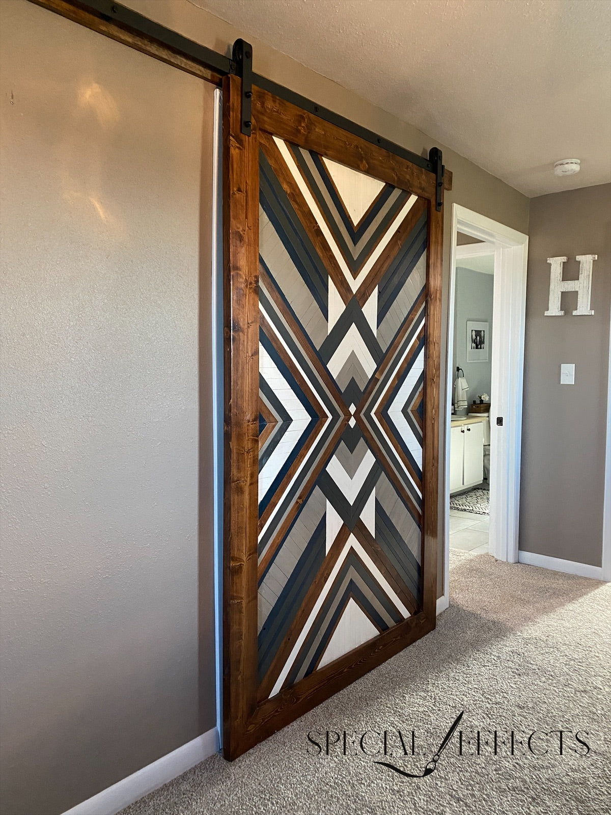 custom geometric wood barn door installed sliding track navy and white bold pattern farmhouse bedroom
